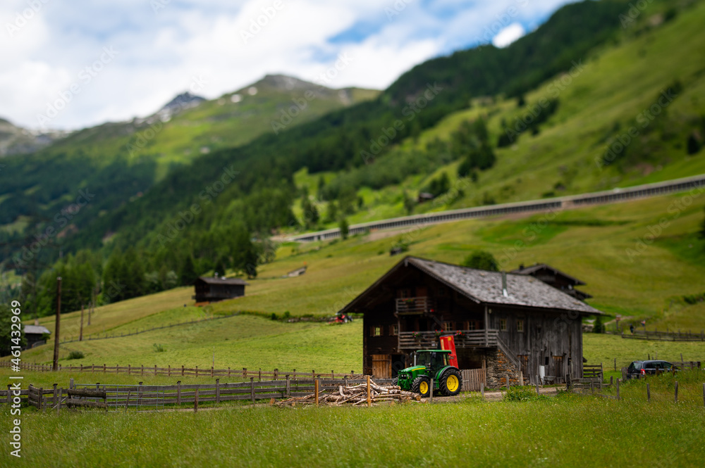 Old small wooden house and green tractor in the alps