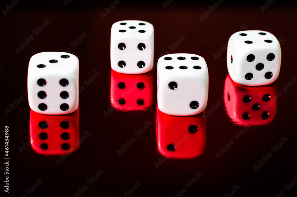 Closeup shot of four dice on a red mirroring surface Closeup shot of four dice on a red mirroring surface
