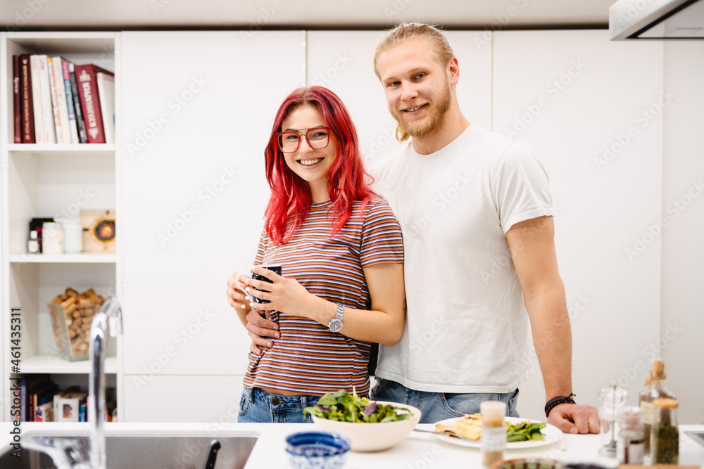 Young white couple laughing while cooking together in kitchen Young white couple laughing while cooking together in kitchen