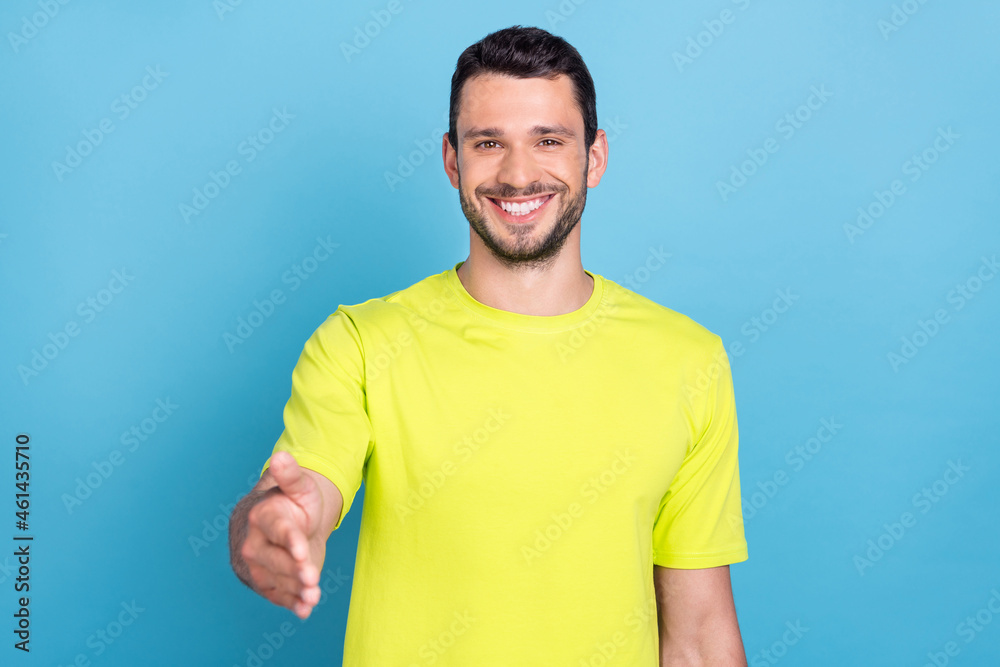 Portrait of attractive cheerful guy shaking giving you hand isolated over bright blue color background