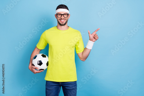 Photo of happy brown haired cheerful man hold hand football point finger empty space isolated on blue color background © deagreez