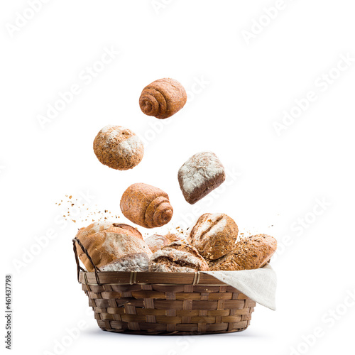 assortment of baked bread falling in straw basket on white background