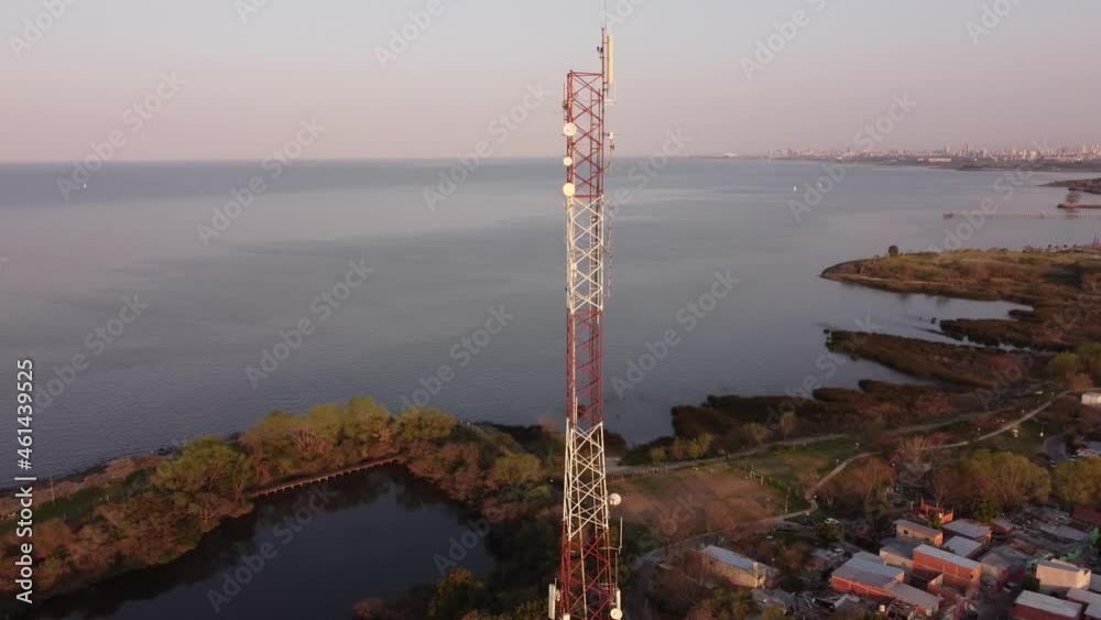Aerial view of a tall antenna near ocean at golden hour. Drone rotation view of a antenna tower near ocean during sunset, Vicente Lopez, Buenos Aires, Argentina. Aerial view of a tall antenna near ocean at golden hour. Drone rotation view of a antenna tower near ocean during sunset, Vicente Lopez, Buenos Aires, Argentina.