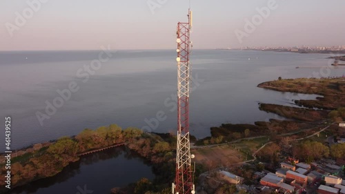 Aerial view of a tall antenna near ocean at golden hour. Drone rotation view of a antenna tower near ocean during sunset, Vicente Lopez, Buenos Aires, Argentina. photo