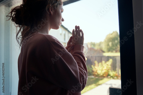 Φωτογραφία Thoughtful depressed young woman looking through the window