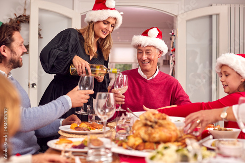 Mother Pouring Wine As Multi-Generation Family Eat Christmas Meal Together
