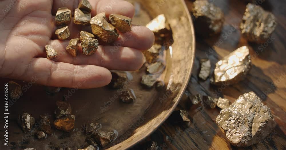 Gold nuggets slowly fall into a copper vintage gold digging bowl. Slow motion 150 fps 4K video. 