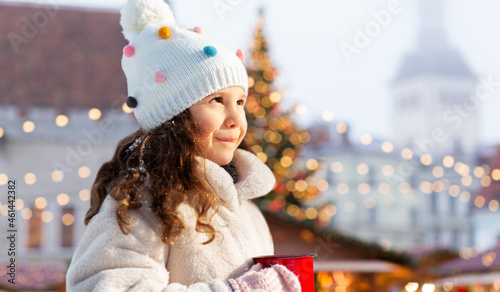 winter holidays and children concept - happy little girl with cup of hot tea over christmas market at old town hall square, tallinn, estonia © Syda Productions
