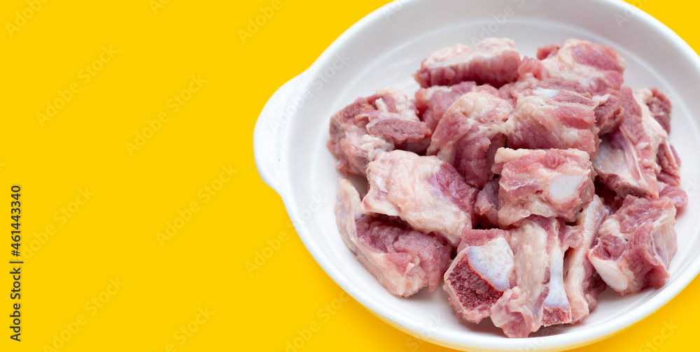 Raw pork ribs in white bowl on yellow background. Raw pork ribs in white bowl on yellow background.