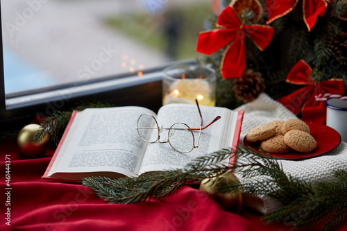 reading, holidays and leisure concept - close up of open book and glasses on christmas at home photo