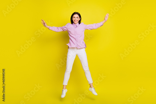 Full length photo of hooray brown hairdo young lady jump wear pink shirt pants isolated on yellow color background