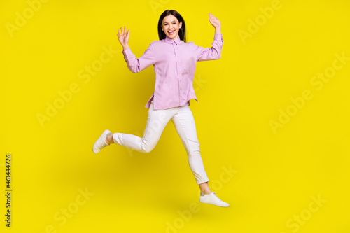 Full body photo of funky brown hairdo young lady run arms up wear pink shirt pants isolated on yellow color background