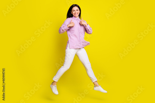 Full length body size view of attractive cheery girl jumping showing two thumbup ad isolated over bright yellow color background