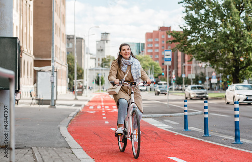 traffic, city transport and people concept - happy smiling woman riding bicycle along red bike lane or two way road on street