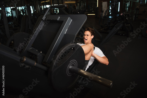 sportsman shouting while working out on leg extension exercising machine in sports center.