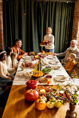 Happy Thanksgiving dinner party with family and friends with turkey and holiday traditional food, dishes on table.