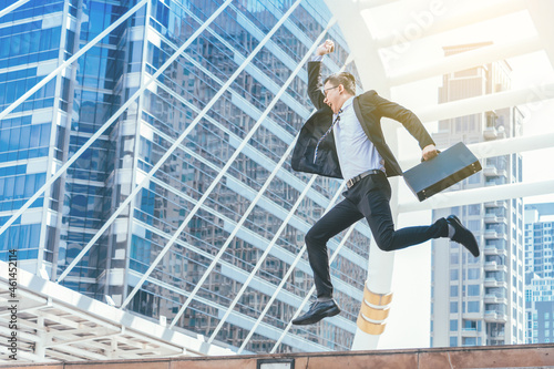 Successful businessman celebrating his victory with jump up in feeling happy on cityscape background.