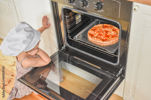 the girl child cooks pizza in the oven photo without filter