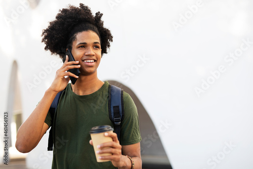 Handsome African man drinking coffee outdoors. Urban guy talking to the phone