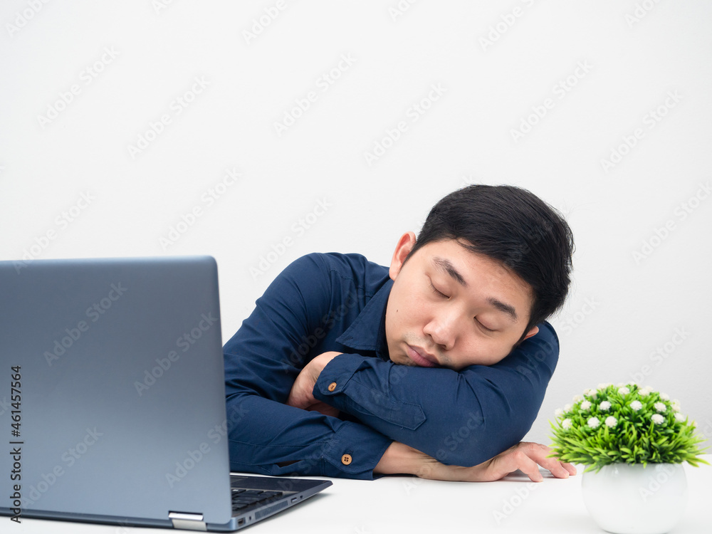 Asian man sleep with his laptop on the table tried about work from home Asian man sleep with his laptop on the table tried about work from home