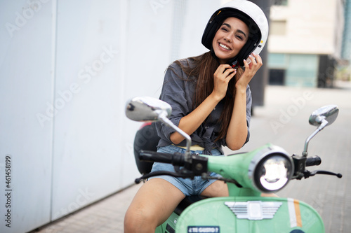 Attractive woman riding scooter in the city. Beautiful happy lady having fun outdoors.