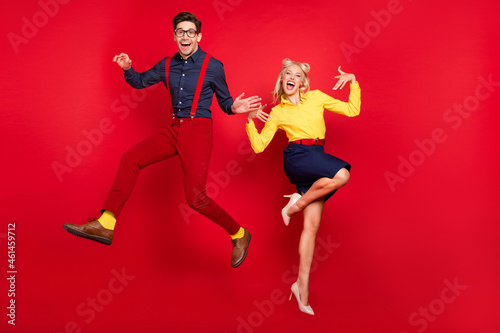 Full length body size view of attractive cheerful couple jumping fooling dancing jive lindy isolated over bright red color background