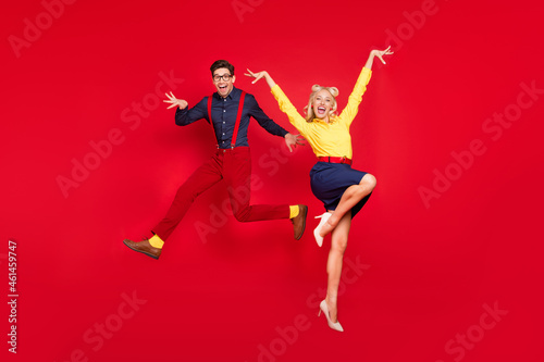 Full length body size view of trendy cheerful crazy couple jumping dancing boogie twist isolated over bright red color background