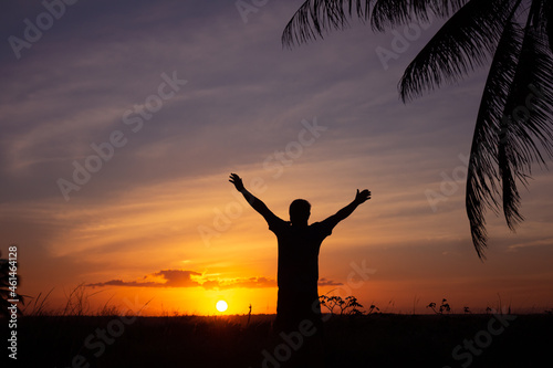 Silhouette of an adult man with arms outstretched in an attitude of happiness. Happy man at sunset.