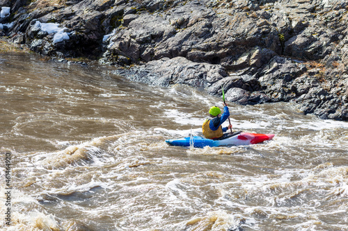 multi-colored kayak in the waters of a turbulent mountain river. the man is rowing against the current