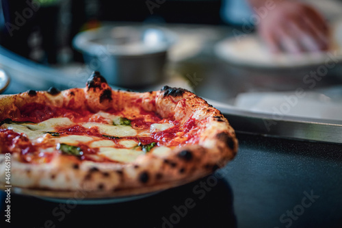 prepared italian pizza after baking with cook in the background making one dough 