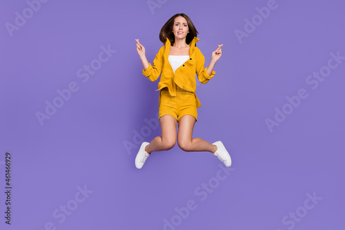 Full body photo of sad young lady jump wear yellow suit sneakers isolated on violet background
