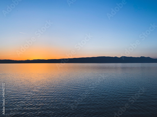 Idyllic orange sunset at the lake, silhouette of the mountains background © Oksana