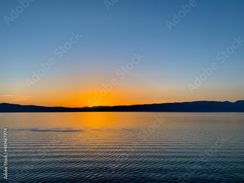 Idyllic orange sunset at the lake  silhouette of the mountains background