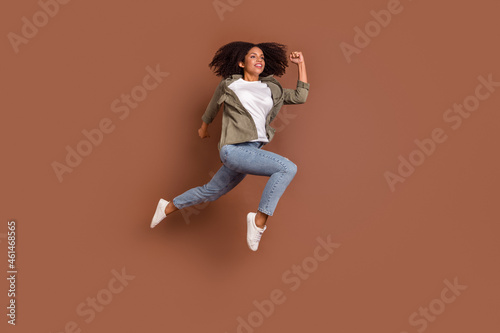 Fototapeta Naklejka Na Ścianę i Meble -  Full length profile photo of cool young brunette lady run wear shirt jeans shoes isolated on brown background