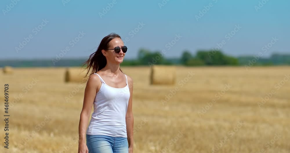 Portrait, a beautiful woman in sunglasses is walking on a golden field and smiling, she is happy. Young and beautiful woman is walking through a wheat field, a romantic walk. 4k, ProRes Portrait, a beautiful woman in sunglasses is walking on a golden field and smiling, she is happy. Young and beautiful woman is walking through a wheat field, a romantic walk. 4k, ProRes