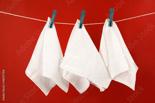 Three handkerchiefs hanging on rope against red background