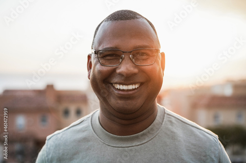 Happy senior african man looking at camera outdoors at sunset - Focus on face photo