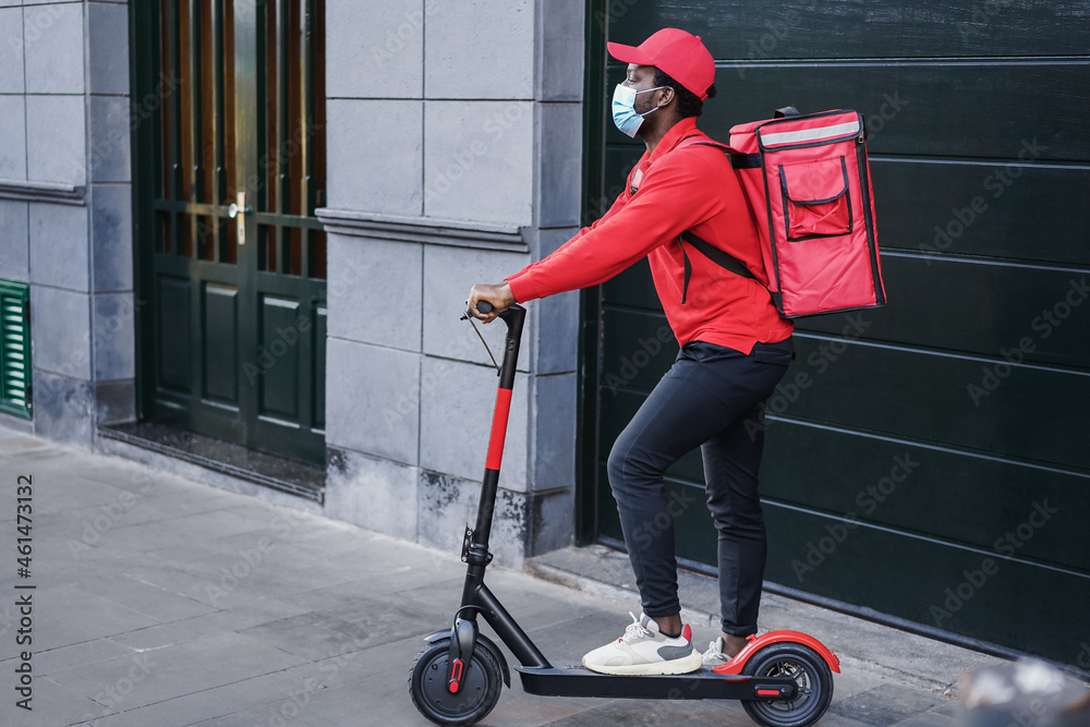African rider delivering meal with electric scooter - Focus on face African rider delivering meal with electric scooter - Focus on face