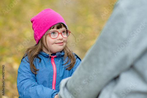 Little girl with special needs talks with her mother at autumn park
