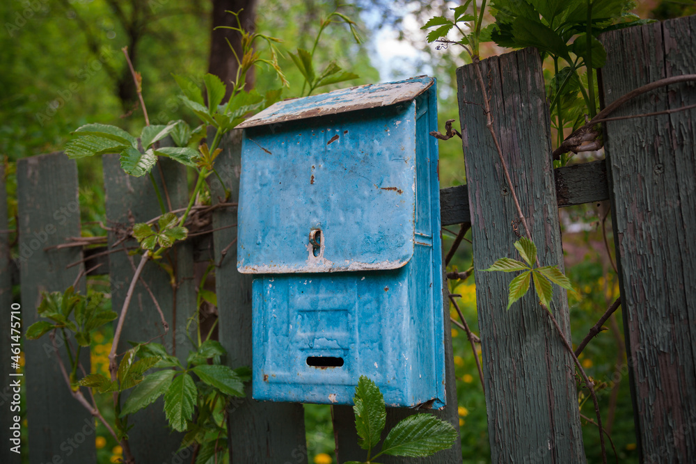 An old rusty mailbox is hanging on the fence. An old rusty mailbox is hanging on the fence.