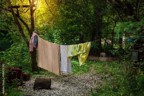 Laundry is dried on a rope in the yard. Old things in the background. An old courtyard in the shade of trees.