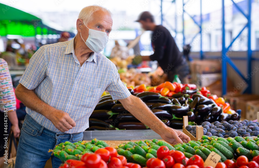 retired european man wearing medical mask protecting against virus buying tomatoes in market retired european man wearing medical mask protecting against virus buying tomatoes in market