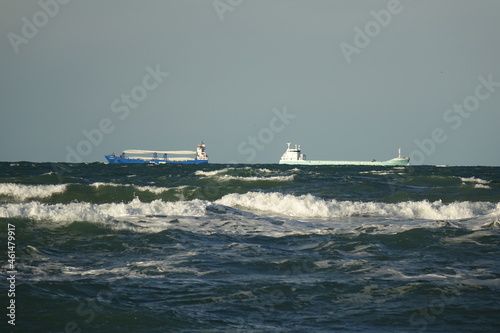 Rough waters at Skagen Nordstrand with two cargo ships in the background near Cape Grenen, meeting point of Skagerrak and Kattegat and the northernmost point of Denmark, Skagen, Northern Jutland, Denm photo