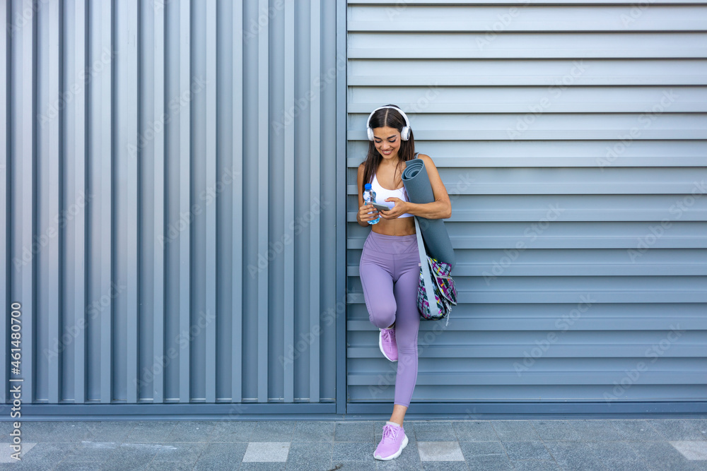Obraz premium Young sporty girl making a break from exercising. Feeling good. Portrait of girl in fitness clothes having a break after workout. Concept of sport technology to enjoy and entertainment.