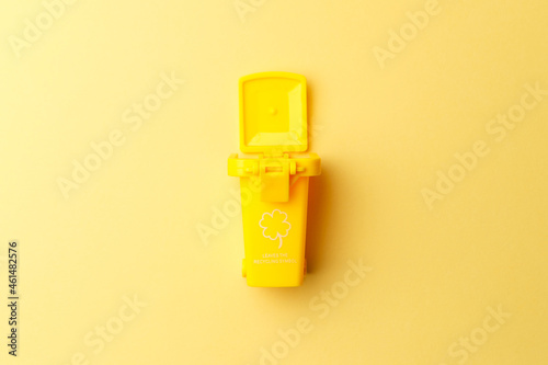 Yellow dumpster on yellow background close-up. Container for disposal garbage waste and save environment. Dustbin for recycle. The concept of ecology. Separate garbage collection