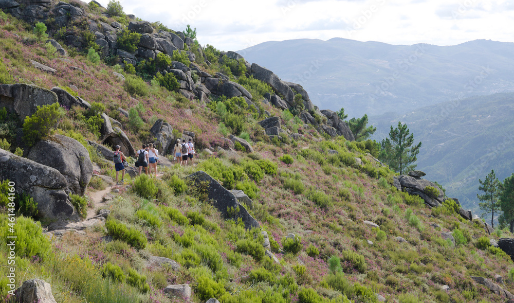 Grupo de pessoas a fazer uma caminhada pela encosta de uma montanha - trilho montanhoso - dia quente de verão