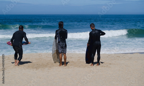 Bodyboard, desporto radical, três homens na praia a praticar bodyboard, dois esperam o melhor momento para ir á água um a correr com a prancha na mão para apanhar uma onda photo