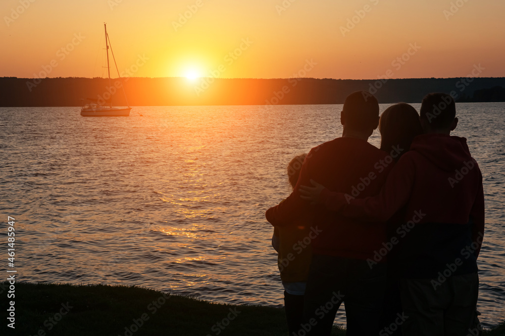 Silhouette of children with parents hugs at sunset, summertime