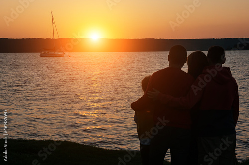 Silhouette of children with parents hugs at sunset  summertime