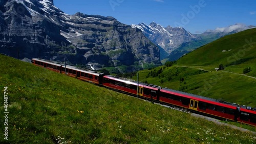 red alpine railway from Kleine Scheidegg to Jungfraujoch. Swiss mountains with Jungfrau, Moench and Eiger. Great scenic view.